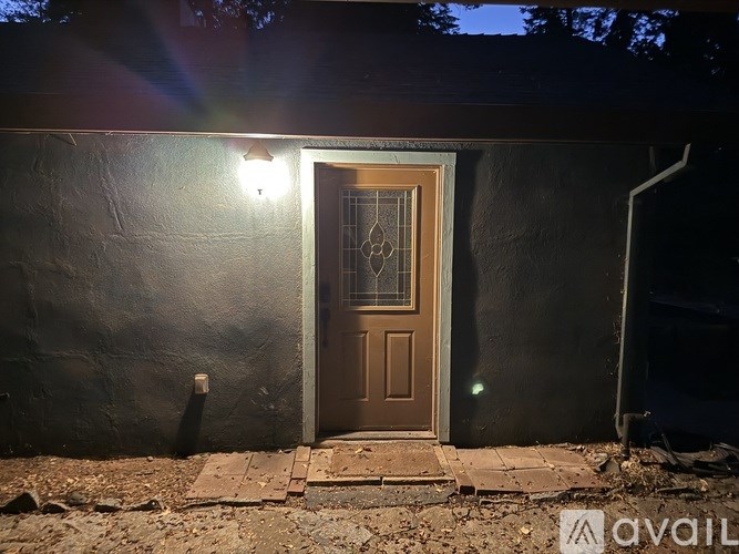 A brown door with a glass window is set in a black wall.