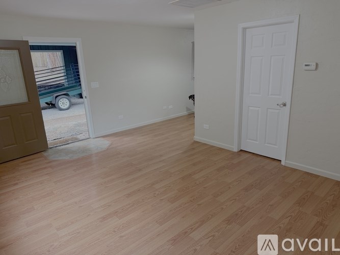 A room with wooden flooring and two doors, one of which is open.