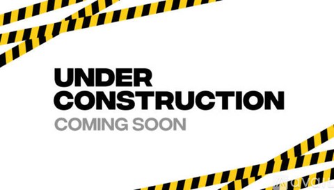 A black and yellow striped construction warning sign with the words "under construction coming soon".