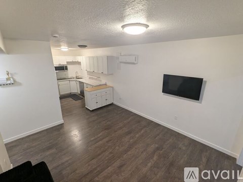 A living room with a television and a kitchen area in the background.