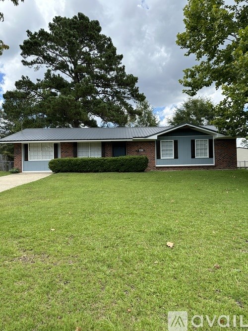 A house with a green lawn and trees in the background.