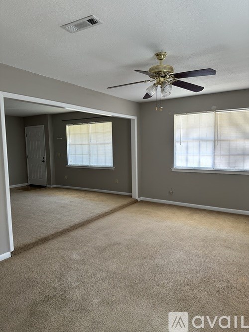 A room with a ceiling fan and carpeted floor.
