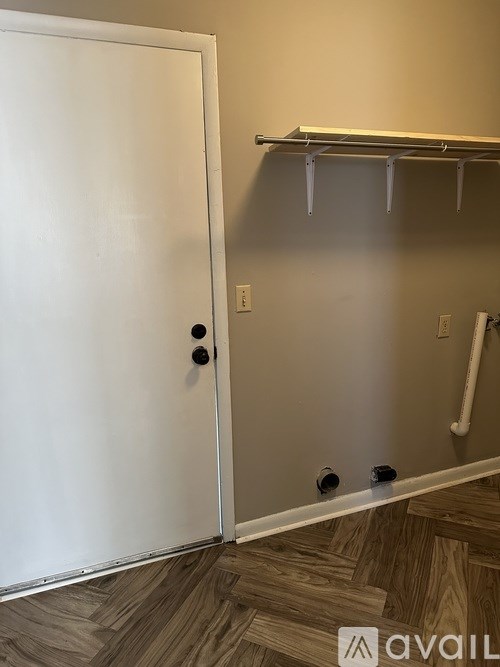 A white door is open to a room with a white pipe on the wall.