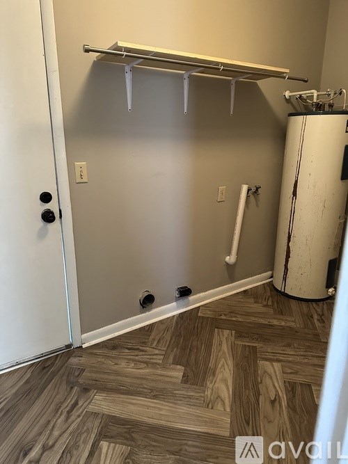 A white door with a black handle is open to a room with a white wall and a white pipe.