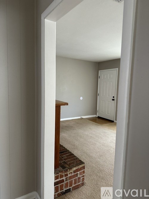 A room with a white door and a brick fireplace.