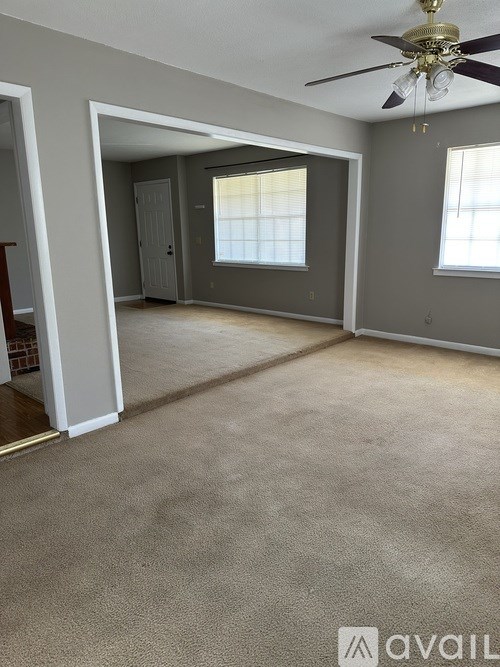 A room with a carpeted floor and a ceiling fan.