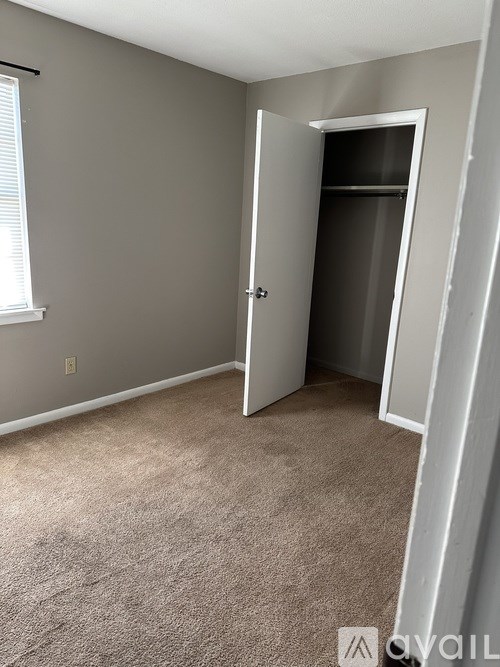 A room with a carpeted floor and a door leading to another room.