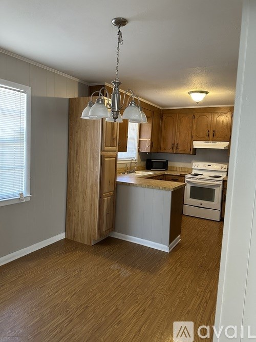 A kitchen with wooden cabinets and a white stove top oven.