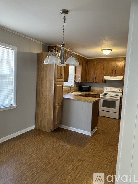 A kitchen with wooden cabinets and a white stove top oven.