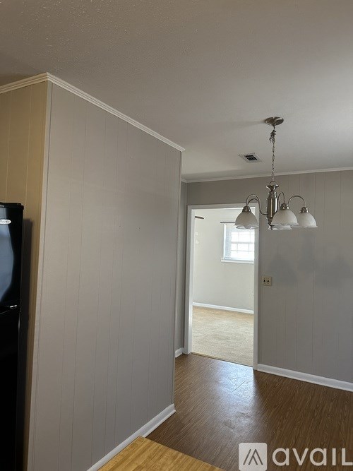 A room with a chandelier and a doorway leading to another room.