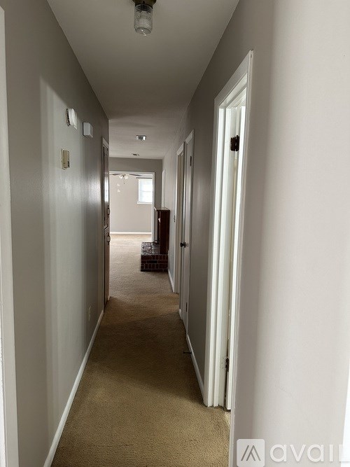 A long hallway with white walls and a carpeted floor.