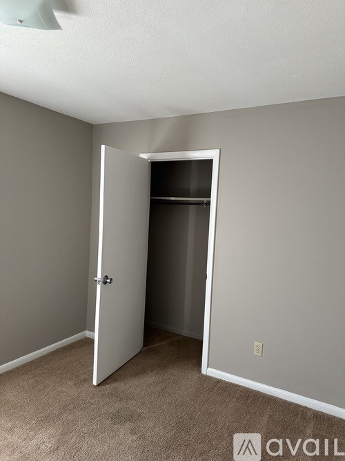 A room with a white door and carpeted floor.