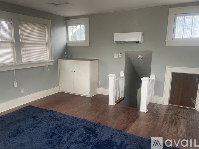 A room with a blue rug and a white cabinet.