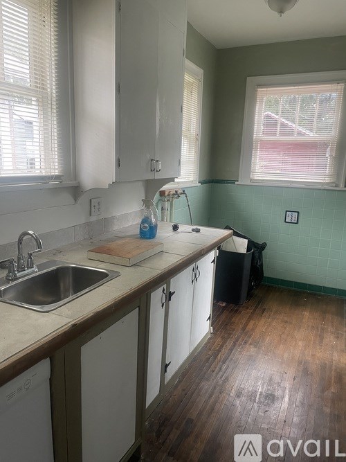 A kitchen with white cabinets and a wooden floor.