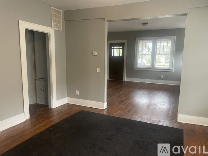A room with a black rug on the floor and a door on the left.