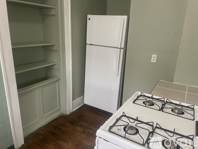 A white refrigerator stands next to a white gas stove in a kitchen.