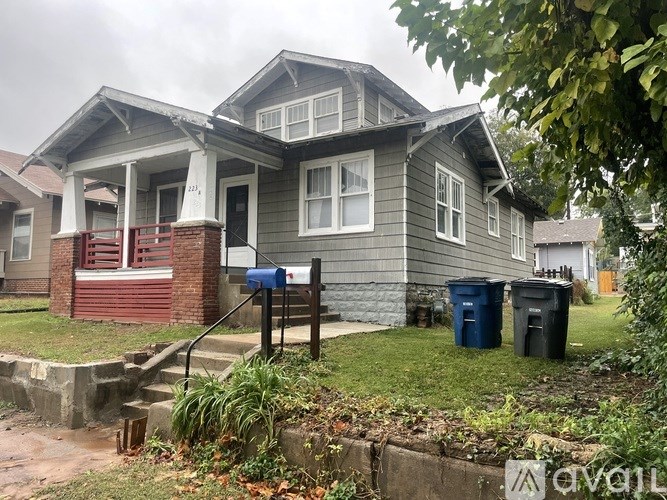 A grey house with a red door and mailbox.
