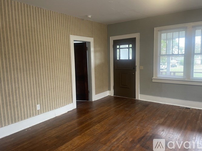 A room with striped wallpaper and wood flooring.