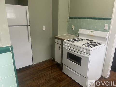 A white gas stove with oven in a kitchen with a white fridge.