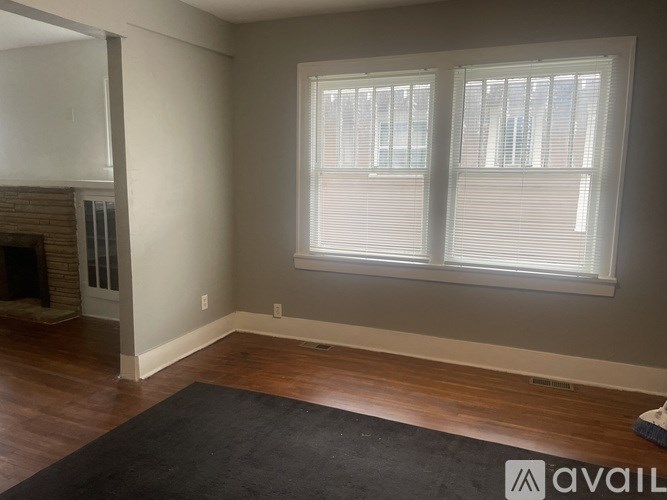 A room with a fireplace and two windows.