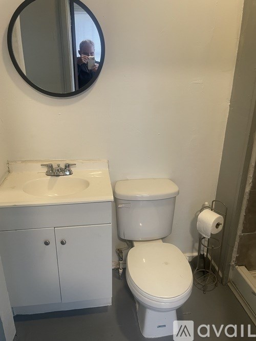 A bathroom with a toilet, sink, and mirror.