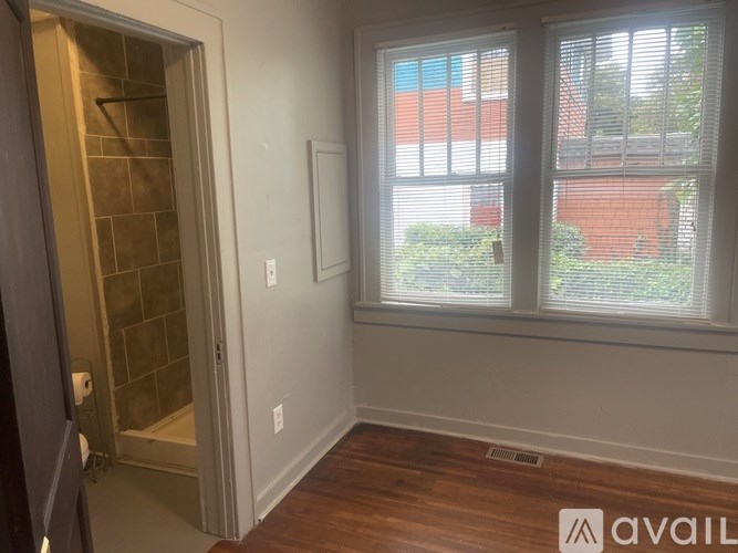 A room with a wooden floor and a window with blinds.