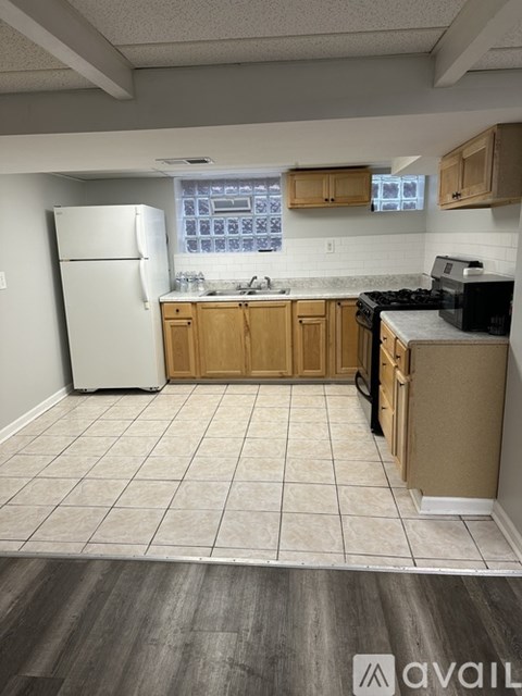 A kitchen with a white refrigerator, wooden cabinets, and a black stove top oven.