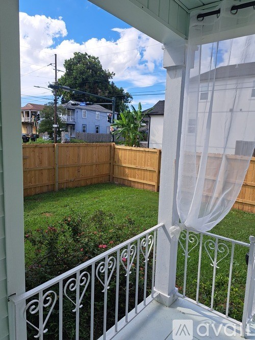 A white balcony with a white railing and a white curtain.