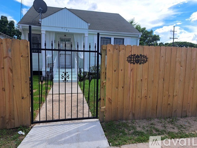 A white house with a black gate and a wooden fence.
