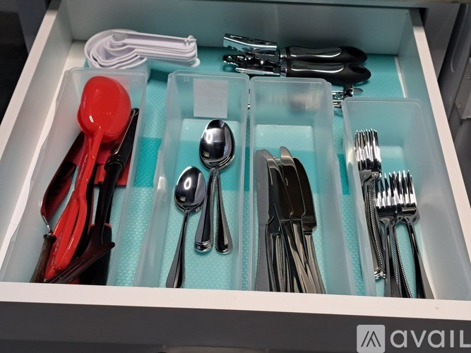 A drawer with compartments holding various utensils.