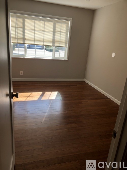 A room with wooden flooring and a window with blinds.