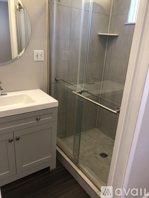 A bathroom with a white sink and a glass shower stall.