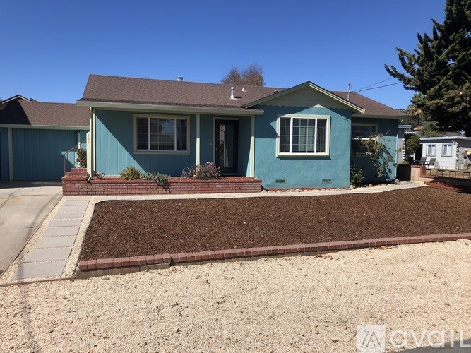 A blue house with a brown roof and a brown front yard.