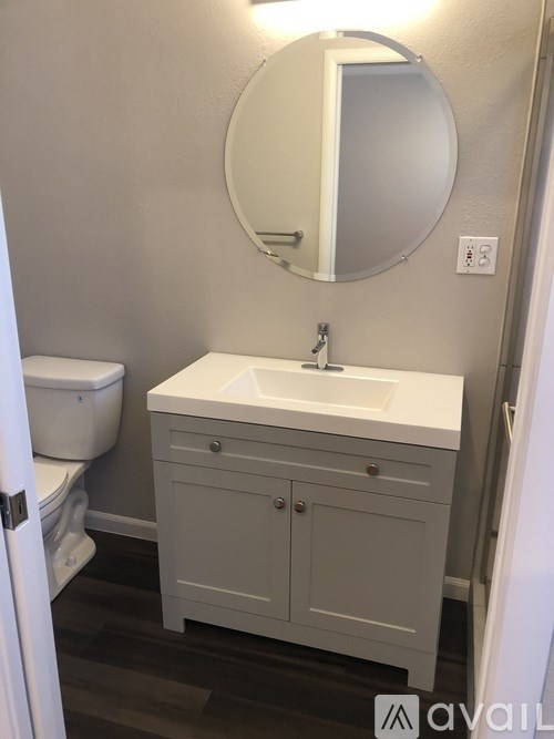 A bathroom with a white sink and a round mirror.
