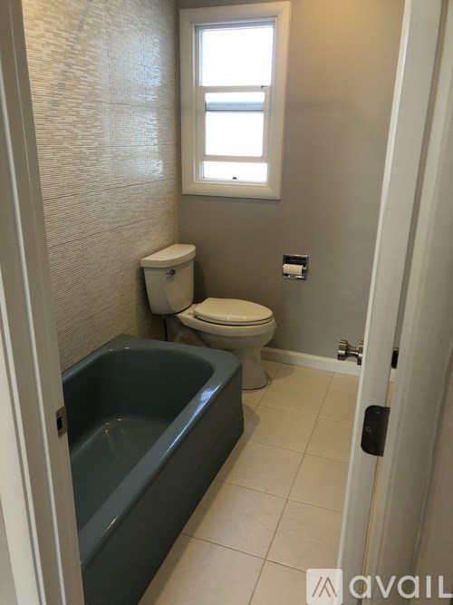 A bathroom with a toilet, tub, and window.