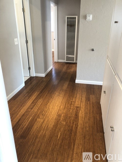 A hallway with wood floors and white walls.