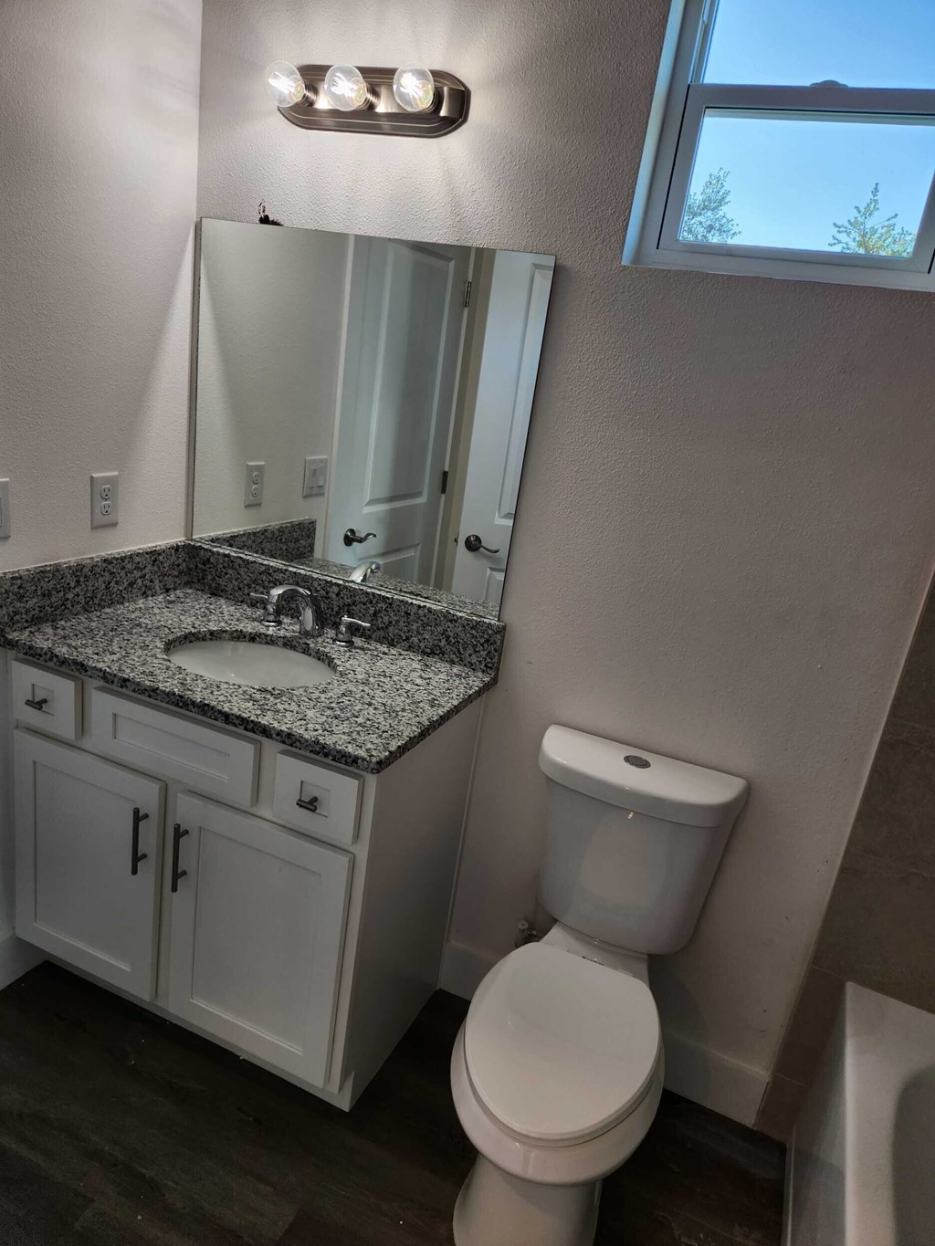 A bathroom with a toilet, sink, and mirror.