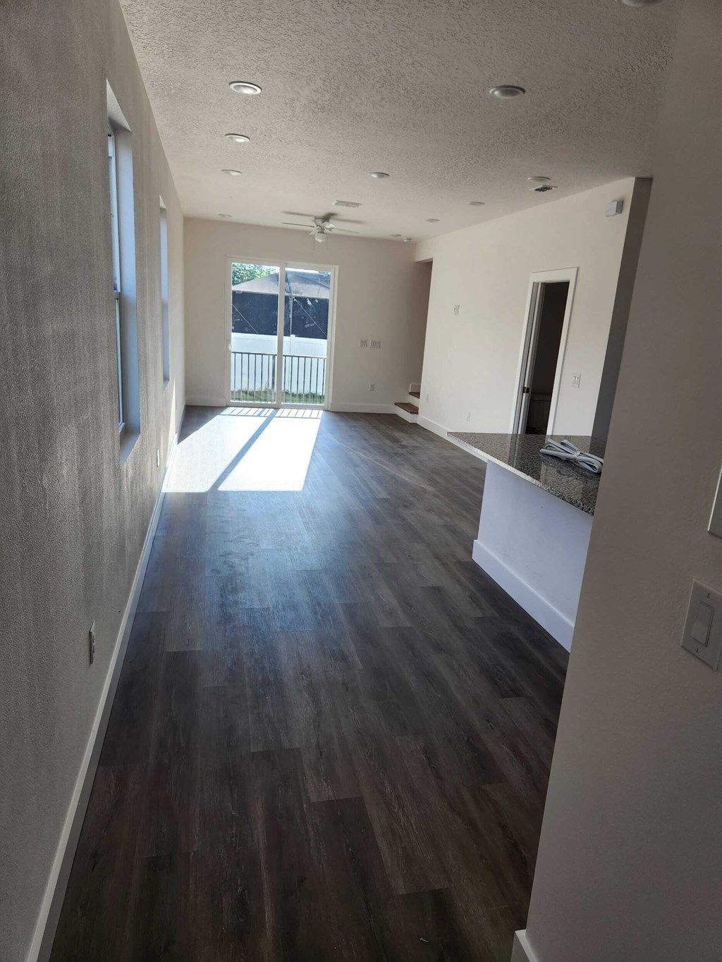 A long hallway with wood floors and white walls.