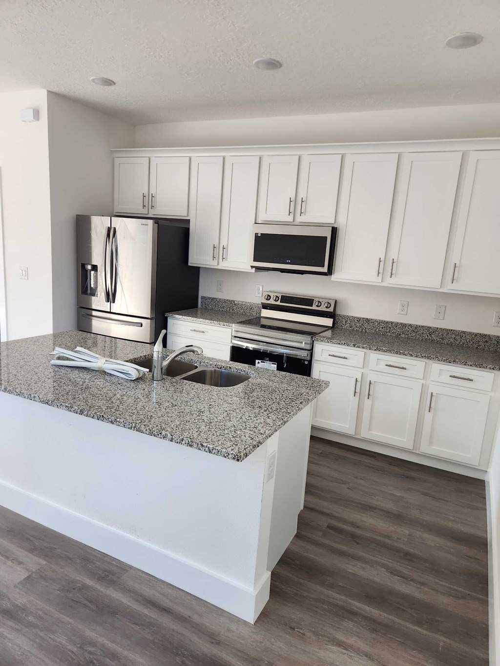 A kitchen with white cabinets and a granite countertop.