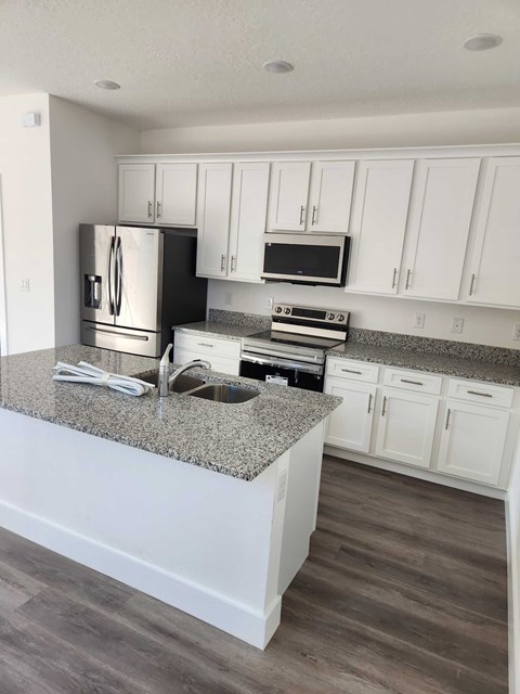 A kitchen with white cabinets and a granite countertop.