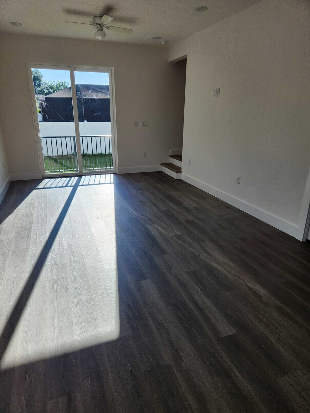 A room with a sliding glass door and a ceiling fan.