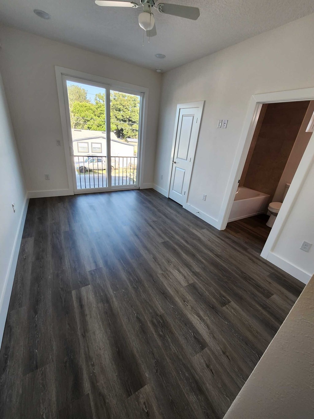 A room with a sliding glass door and wood flooring.
