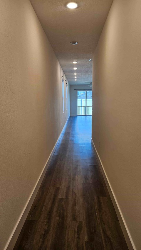 A long hallway with wood floors and white walls.