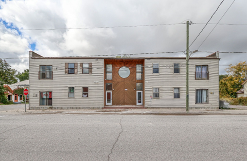 A grey building with a brown door and windows.