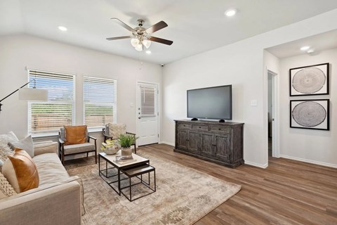 A living room with a couch, a coffee table, a television, and a ceiling fan.