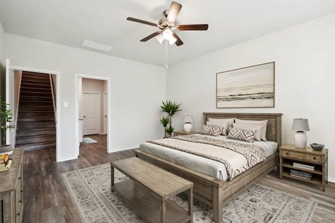 A bedroom with a bed, nightstand, and a ceiling fan.