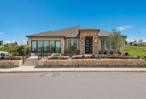 A modern house with a stone wall and glass doors.