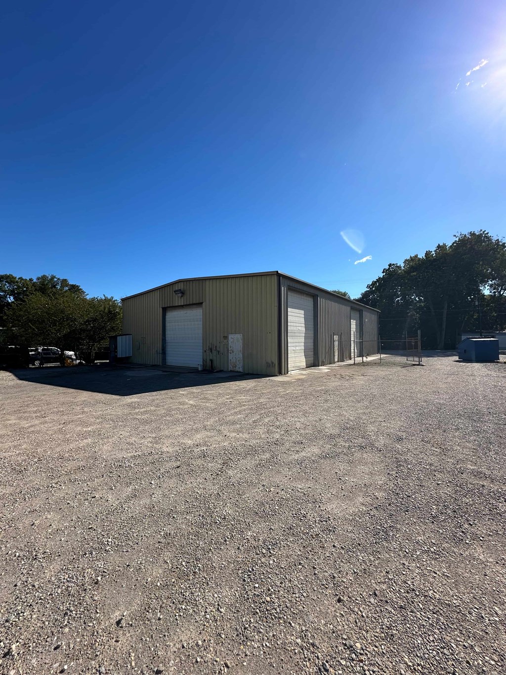 A large industrial building with a gravel lot in front.