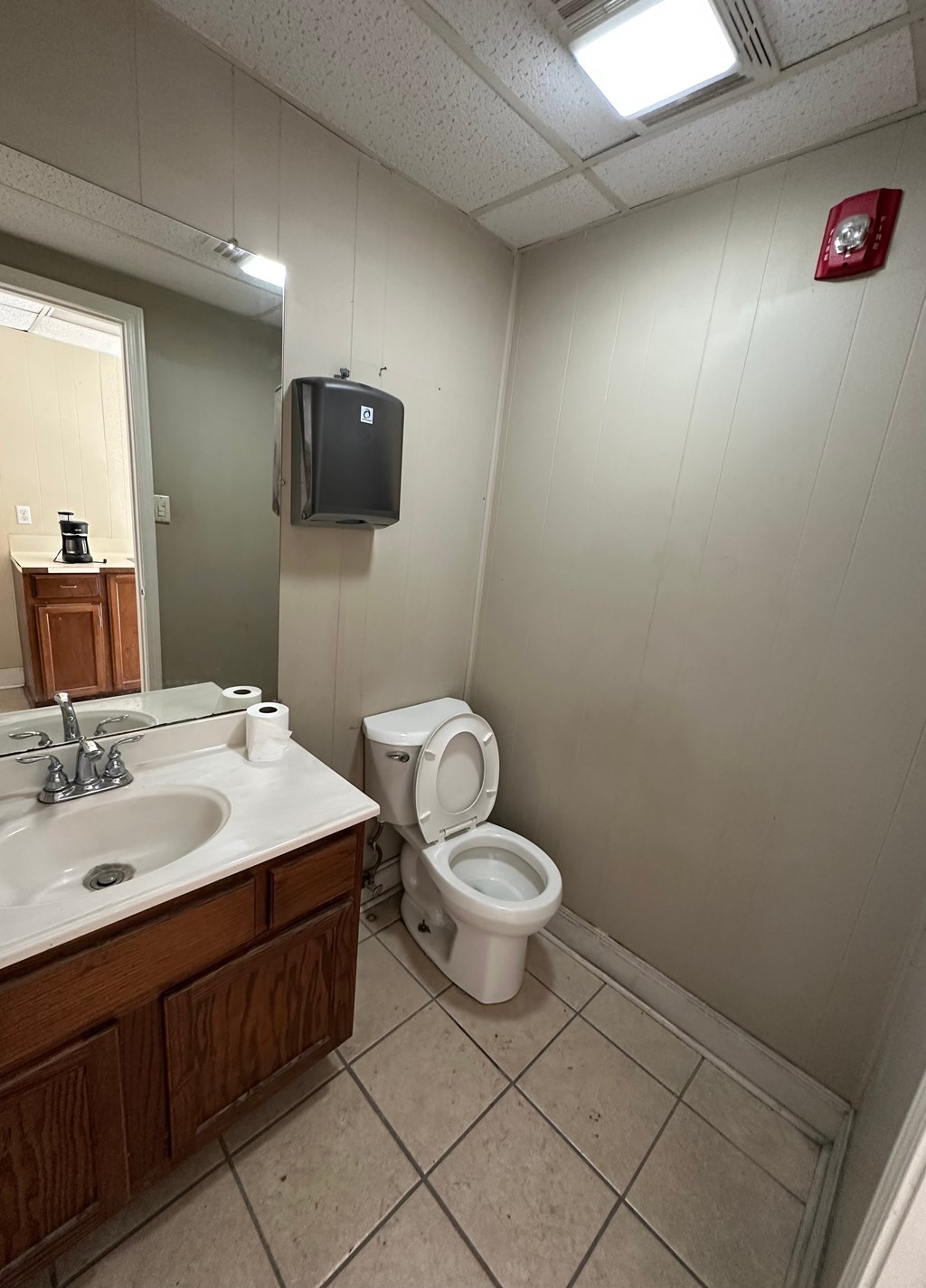 A bathroom with a toilet, sink, and mirror.