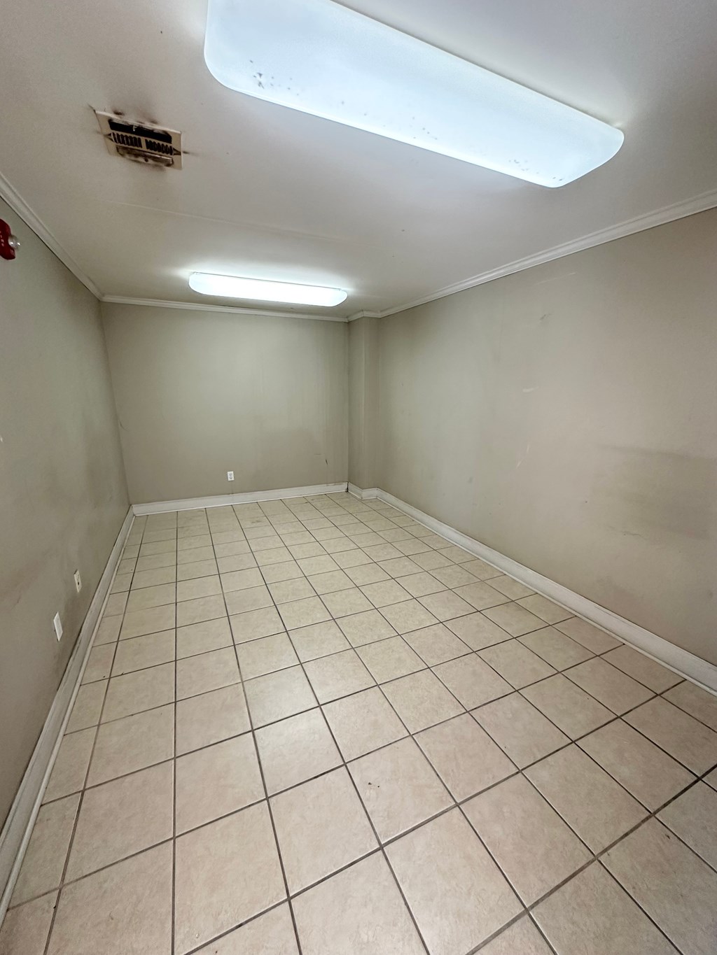 A room with a tiled floor and a fluorescent light on the ceiling.